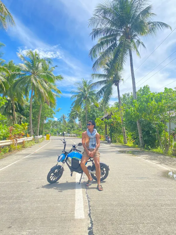 Man sitting on eBike on coconut road, Siargao